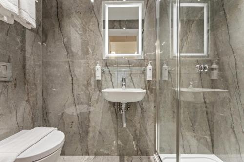 a bathroom with a sink and a toilet and a shower at Cleveland Residences Russell Square in London