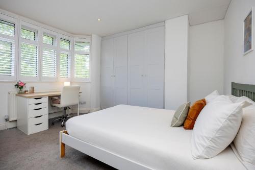 Un dormitorio blanco con una cama y un escritorio. en Veeve - The Garden Home, en Londres