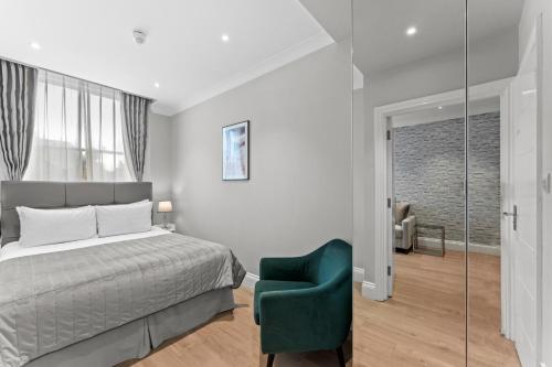 a bedroom with a bed and a green chair at Cleveland Residences Russell Square in London
