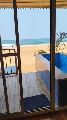 a view of the beach from a room with a window at Darsy Residency and beach cottages in Agonda
