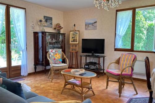 un salon avec un canapé, des chaises et une télévision dans l'établissement House 3 rooms with garden in Gujan-Mestras, à Gujan-Mestras