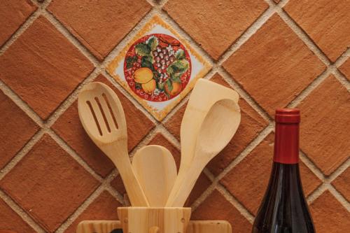 a bottle of wine and wooden spoons and a plate of food at CONVIVIUM - Suites Apartments in Randazzo