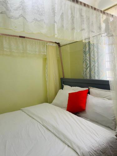 a bed with a red pillow on top of it at Zedek Suites in Nairobi