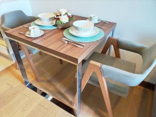 a wooden table with two cups and saucers on it at The Astra Luxury Condo near old town in Chiang Mai