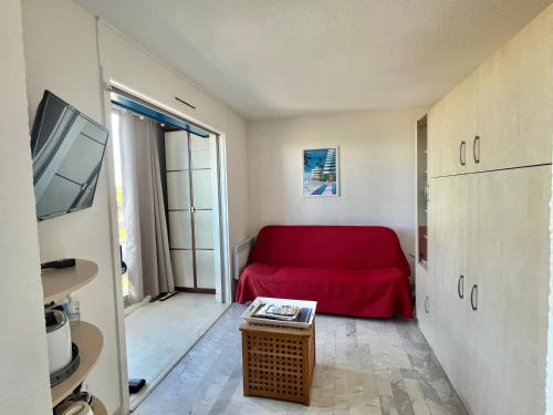 un salon avec un canapé rouge et une télévision dans l'établissement Studio Lumineux avec Terrasse et Parking Privé, à 600m de la Plage - FR-1-716-76, à La Grande Motte