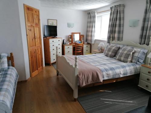 a bedroom with a bed and a dresser and a television at HP Bed and Breakfast in Congleton