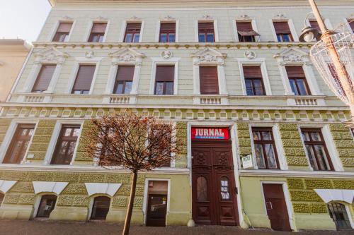 a large yellow and white building with a tree in front at Fabulous Bulevard Ultracentral Apartament in Arad