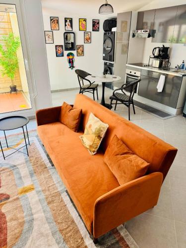 un canapé orange dans un salon avec une cuisine dans l'établissement Stylish City Pad - Walk to All, à Bergerac