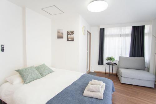 a white bedroom with a bed and a chair at Natsumiホテル 高级独栋别墅301 in Tokyo
