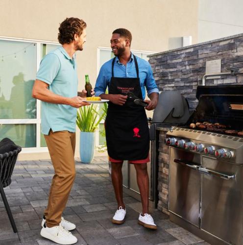 two men standing in a kitchen holding a plate of food at TownePlace Suites by Marriott Mankato in Mankato