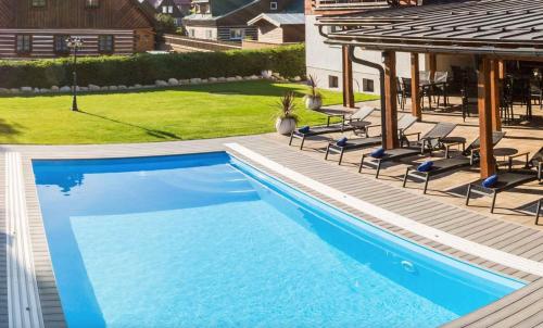a swimming pool with chairs and a gazebo at Chalet Schäfer s vyhřívaným bazénem se slanou vodou in Harrachov