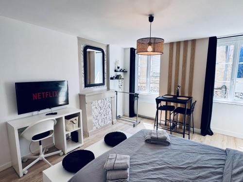 Cette chambre comprend un lit, une télévision et une table. dans l'établissement Logement Moderne au cœur de la ville, à Quimper