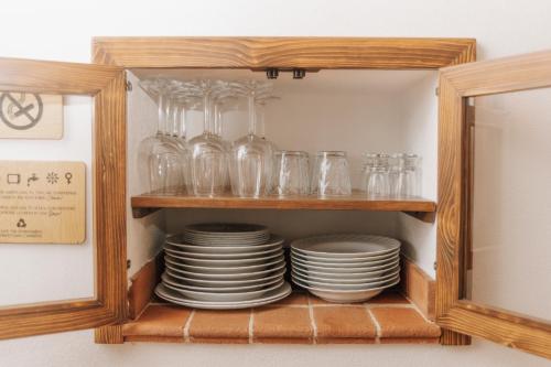 a cabinet filled with plates and glasses on a shelf at CONVIVIUM - Suites Apartments in Randazzo