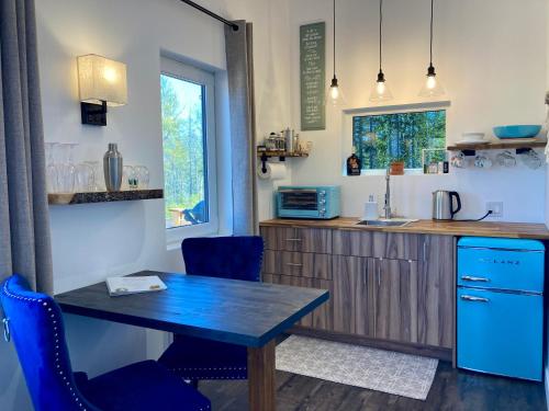 a kitchen with a wooden table and blue chairs at The Snuggy - NEW! Oceanview - Private - Eco-Lux - King Bed - Adults Only! in Ingonish Beach