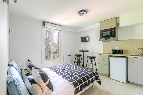 Cet appartement comprend une chambre avec un lit et une cuisine avec une fenêtre. dans l'établissement Studio lumineux à deux pas des commerces- Asnières, à Asnières-sur-Seine