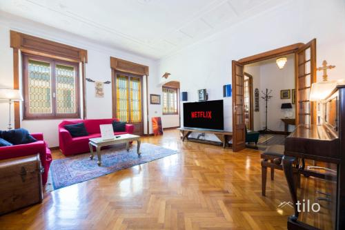a living room with a red couch and a tv at JACUZZI| TERRACE| 2BR| ART GALLERY| By Tilo Lux in Genova