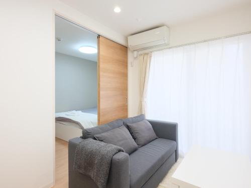 a living room with a couch and a bedroom at 期間限定セール中 - The River Up Palace -ザリバーアップパレス- 三井ｱｳﾄﾚｯﾄﾊﾟｰｸ木更津徒歩9分 ﾌﾟﾛｼﾞｪｸﾀｰや駐車場付の1LDK in Kisarazu