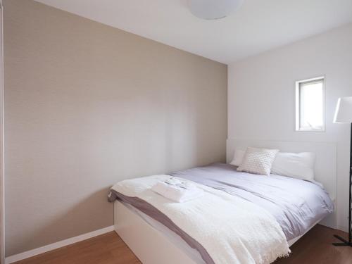 a small bedroom with a bed with white walls at 期間限定セール中 - The River Up Palace -ザリバーアップパレス- 三井ｱｳﾄﾚｯﾄﾊﾟｰｸ木更津徒歩9分 ﾌﾟﾛｼﾞｪｸﾀｰや駐車場付の1LDK in Kisarazu