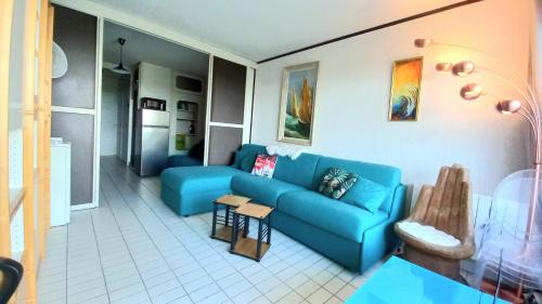 a living room with a blue couch and a kitchen at Le Cocon de Flo, studio face à la mer au couchant in La Grande-Motte