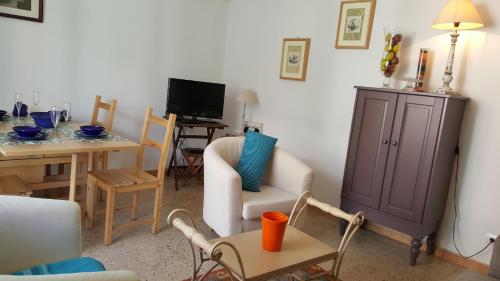 een woonkamer met een stoel, een tafel en een tv bij Apartamento Hector en Sitges in Sitges