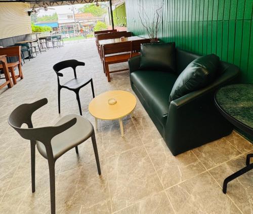 ein Wohnzimmer mit Couch, Stühlen und Tischen in der Unterkunft Green Terrace Residence Phuket in Kathu
