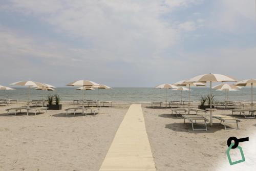 einen Strand mit Tischen, Stühlen und Sonnenschirmen in der Unterkunft HOTIDAY Room Collection - Milano Marittima in Milano Marittima