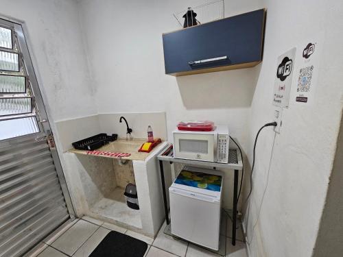 a small kitchen with a microwave on a counter at Kitnet in Guarulhos