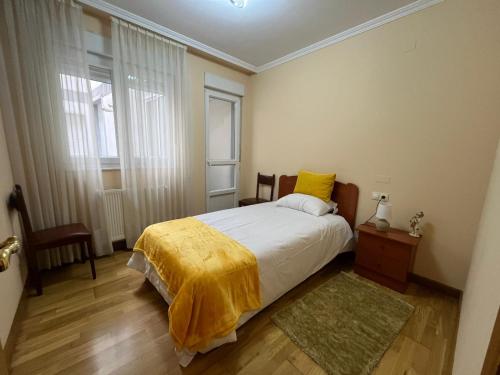 a bedroom with a bed with a yellow blanket on it at Apartamento Los Gallegos in Foz
