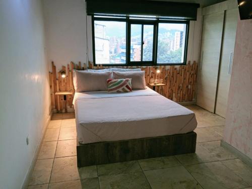 a large bed in a room with a window at Tauro Black Suites Cerca al estadio Atanasio Girardot in Medellín