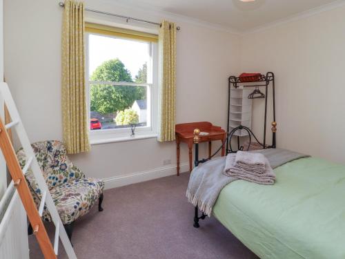 a bedroom with a bed and a chair and a window at Poets Retreat in Cockermouth