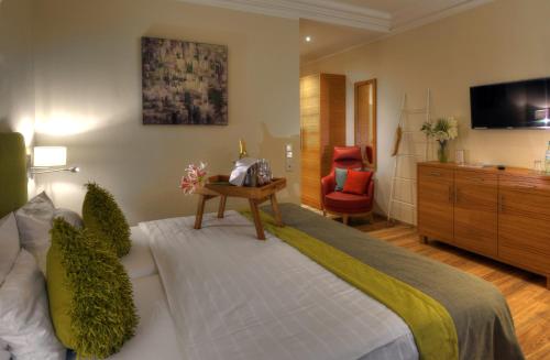 a bedroom with a bed and a dresser and a tv at Nells Park Hotel in Trier