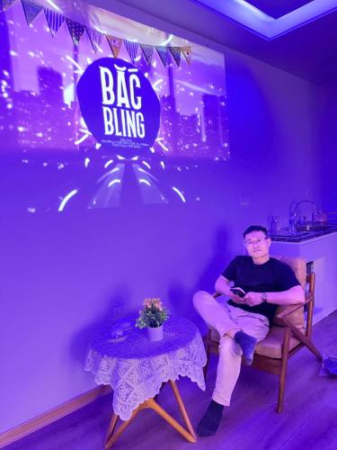 a man sitting in a chair in a room with a big dining sign at Vu'Stay in Binh Hai