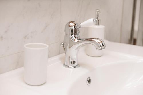 a bathroom sink with a faucet and a roll of toilet paper at CONVIVIUM - Suites Apartments in Randazzo