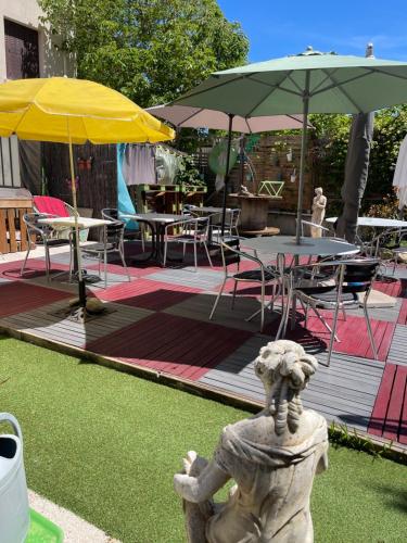 a statue in front of a patio with tables and umbrellas at Hotel Clair Logis in Argelès-sur-Mer
