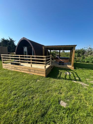 a cabin in a field with a gazebo at Dolafon Luxury Glamping Pod 2 With Hot Tub in St Asaph