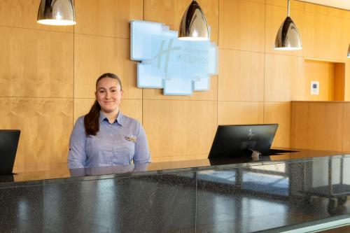 a woman is standing behind a counter in an office at Holiday Inn Express London - Epsom Downs by IHG in Epsom