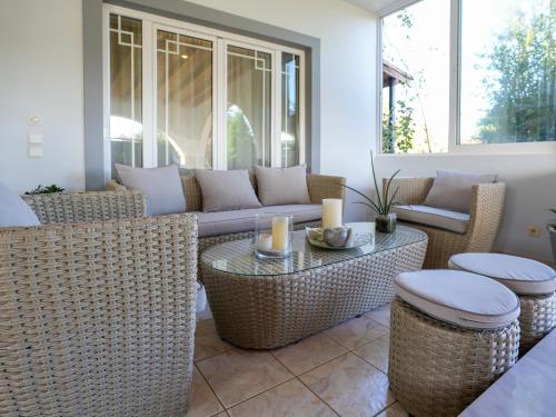 a patio with wicker chairs and a couch and tables at Villa Elysian in Antimácheia