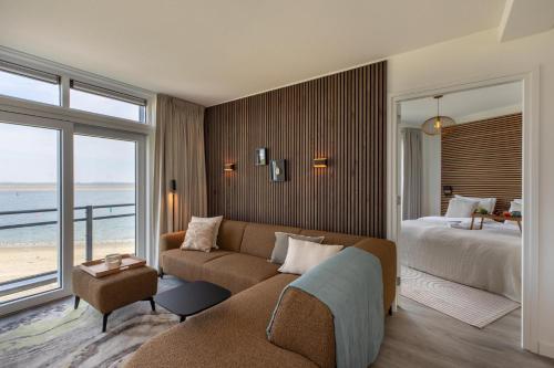 a living room with a couch and a bed and a bedroom at Vakantiewoning aan het water 'Oester Oase' - met 2 balkons - Vista Maris - Nr 36 in Sint Annaland
