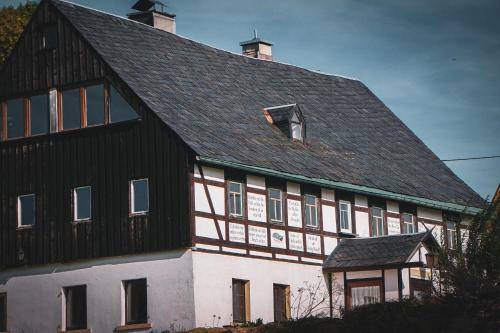 a large black and white building with a roof at Landhaus Bärenstein - Pano-Blick 1 in Bärenstein