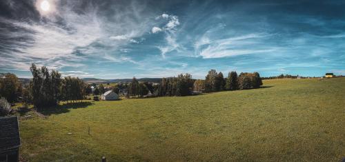 a large green field with trees and a blue sky at Landhaus Bärenstein - Pano-Blick 1 in Bärenstein