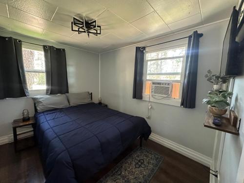 a bedroom with a blue bed and two windows at Cabin Getaway with Lake View! in Coeur d'Alene