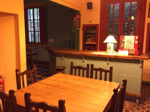 a dining room with a wooden table and a bar at Casa Chango Hostel in Tandil