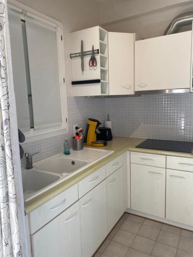 une cuisine avec des armoires blanches et un évier dans l'établissement T4-72 m2 Vue Panoramique - 200 m de la plage - Etage 5 avec Ascenseur -6 pers max, à Sète