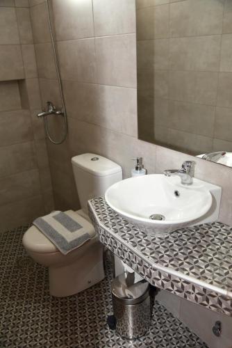 a bathroom with a sink and a toilet and a mirror at Evanthia Toroz Rooms & Studios in Mithymna