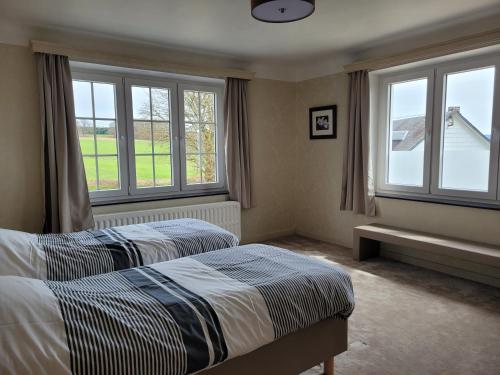a bedroom with two beds and two windows at Cottage Fauna & Flora in Malmedy