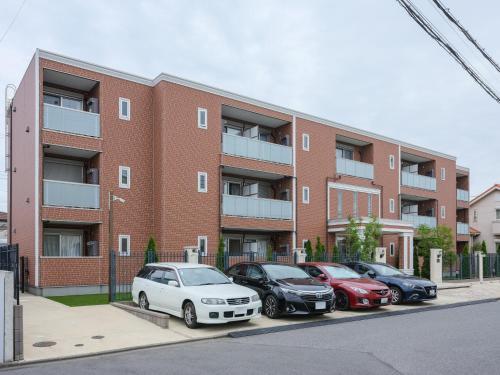 a group of cars parked in front of a brick building at 期間限定セール中 - The River Up Palace -ザリバーアップパレス- 三井ｱｳﾄﾚｯﾄﾊﾟｰｸ木更津徒歩9分 ﾌﾟﾛｼﾞｪｸﾀｰや駐車場付の1LDK in Kisarazu