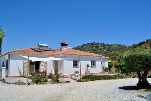 a white house with a mountain in the background at Sobremesa Boutique in Sayalonga