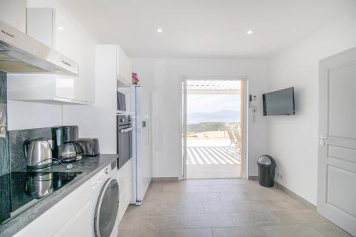 La cuisine blanche est équipée d'un évier et d'un réfrigérateur. dans l'établissement Bel Appartement Neuf, Climatisé, à Albitreccia