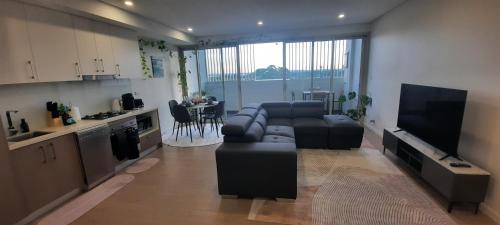 a living room with a couch and a tv and a kitchen at Stylish 1Bedroom Apartment with Study and Parking Near Sydney Airport in Sydney
