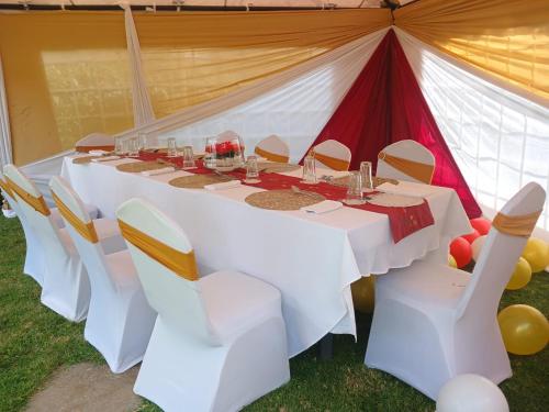Una mesa larga blanca y sillas en una carpa. en Jafra Elephant inn, en Eldoret